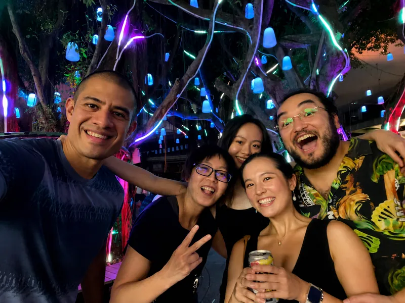 Friends smiling together under colorful lights at night