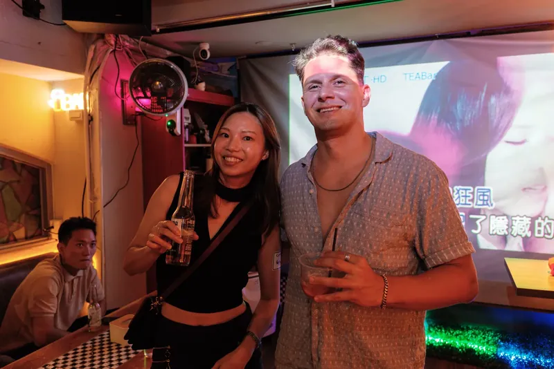 Two guests posing beside the karaoke screen
