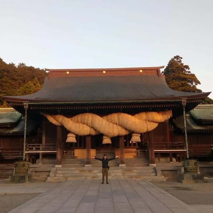 Yi standing in front of a shrine during a trip